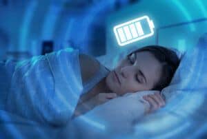 Woman sleeping under image of charging battery